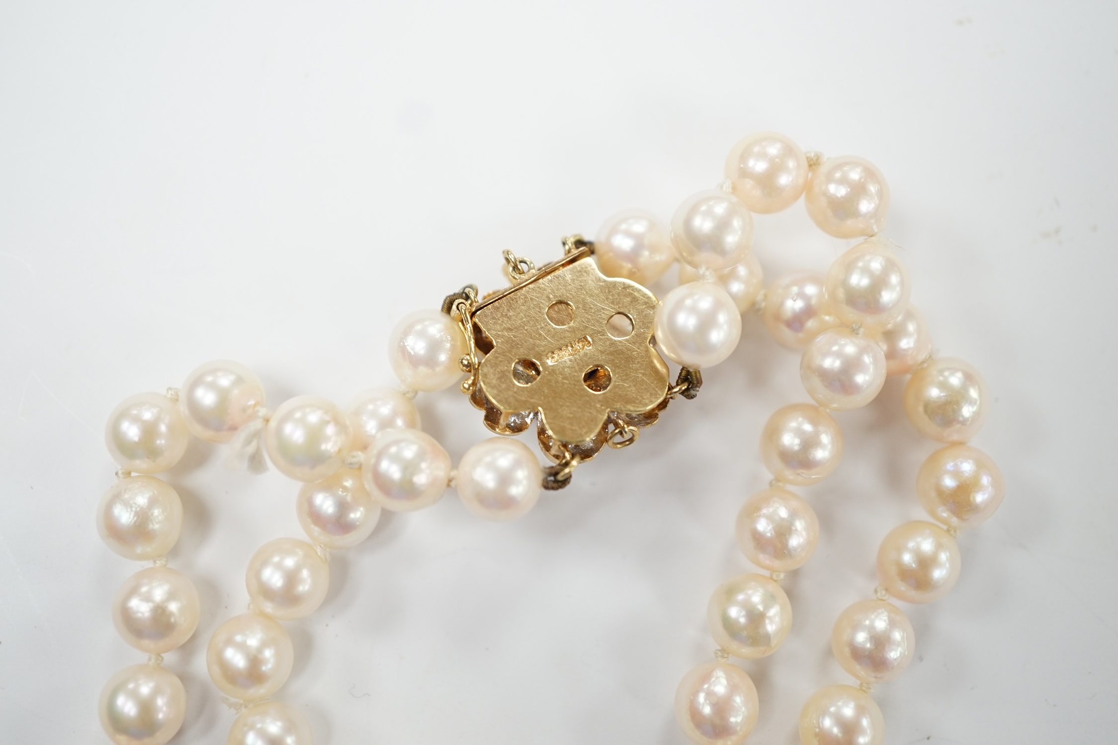 A double strand cultured pearl necklace, with cabochon sapphire and diamond chip cluster set 14k clasp, 44cm. Good condition.